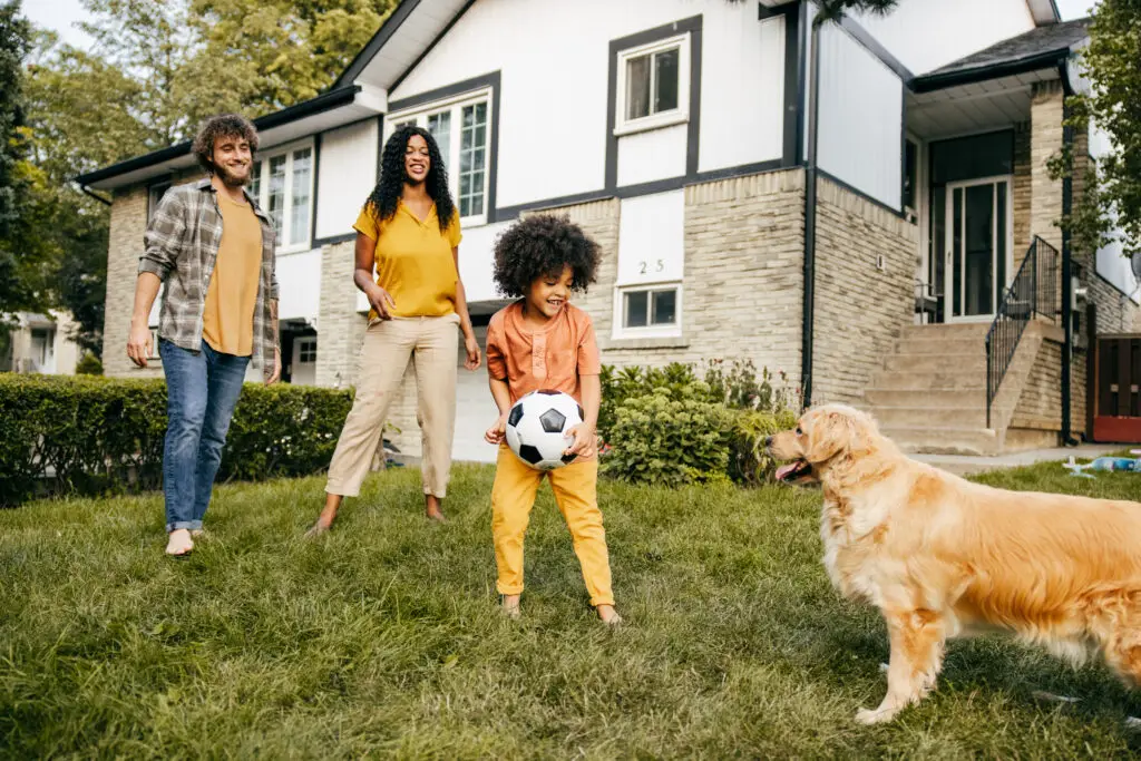 Child playing with dog outside, family behind - enjoying a pest free yard.