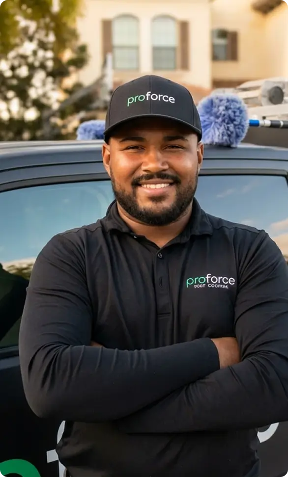 Smiling man in a black proforce pest control uniform stands with arms crossed in front of a Commercial Template work vehicle.