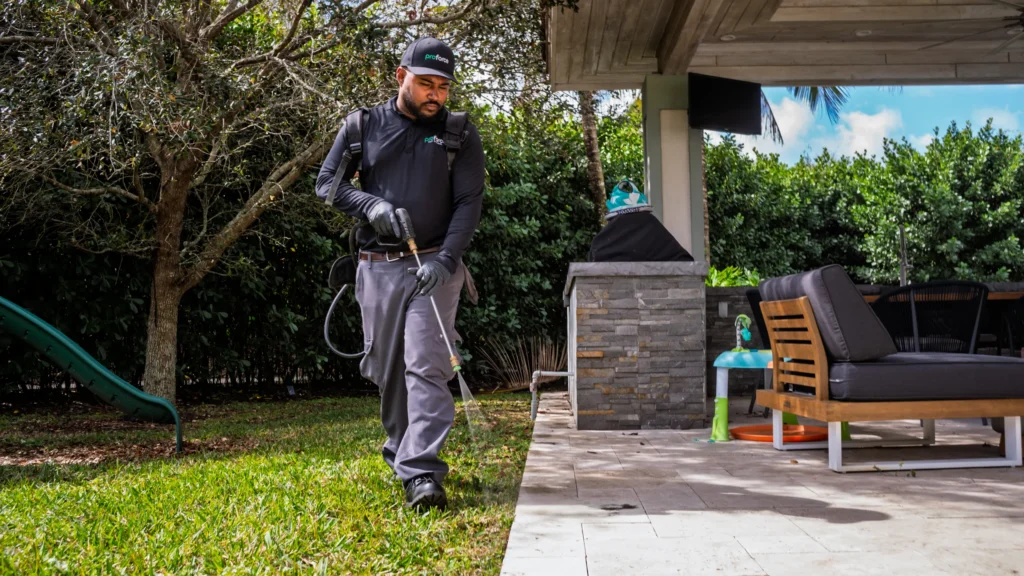 A Proforce pest control worker sprays chemicals along the patio edge for effective home protection.