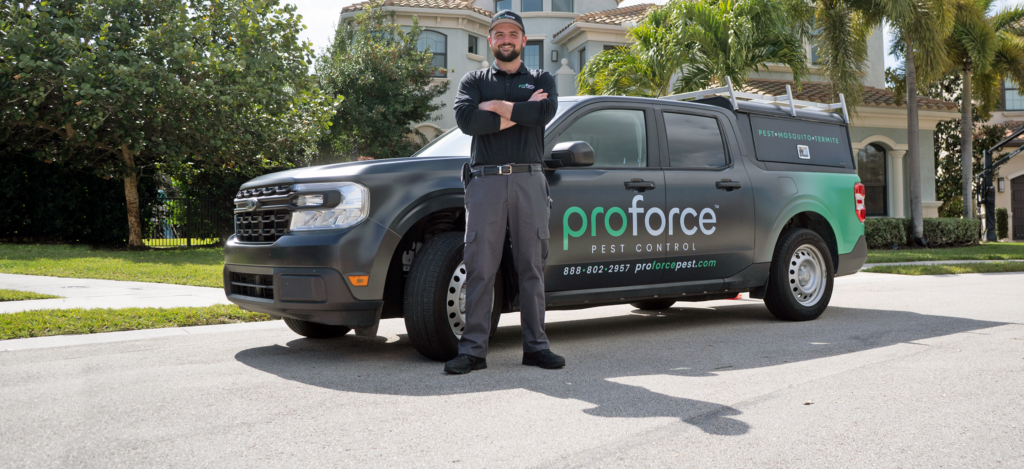 A proforce technician is standing in front of their service truck at a customers home.